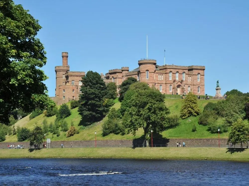 a castle sitting on top of a hill next to a lake at Inverness City Apartment in Inverness