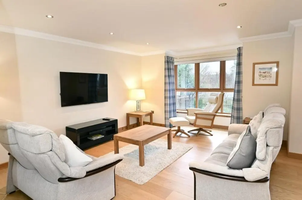 a living room with two chairs and a flat screen tv at Inverness City Apartment in Inverness