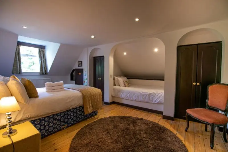a large bedroom with two beds and a chair at Cortes House in Fraserburgh