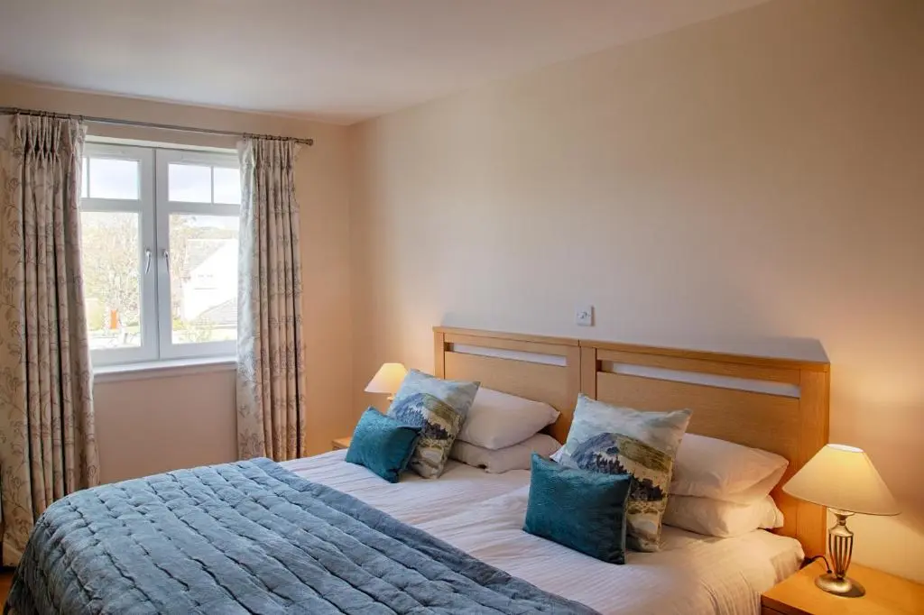 a bedroom with a bed with blue pillows and a window at Links Apartment in Brora