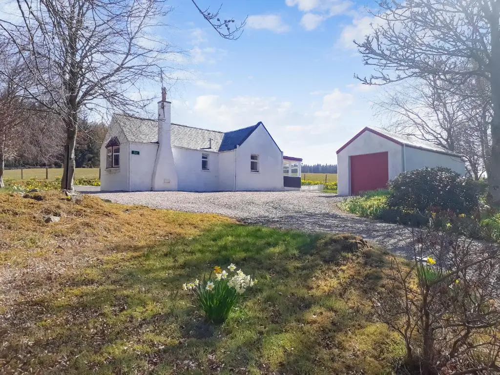 a white barn with a red door on a field at Ivy Cottage in Mountblairy