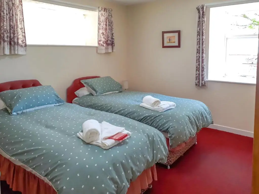 two beds in a room with towels on them at Ivy Cottage in Mountblairy
