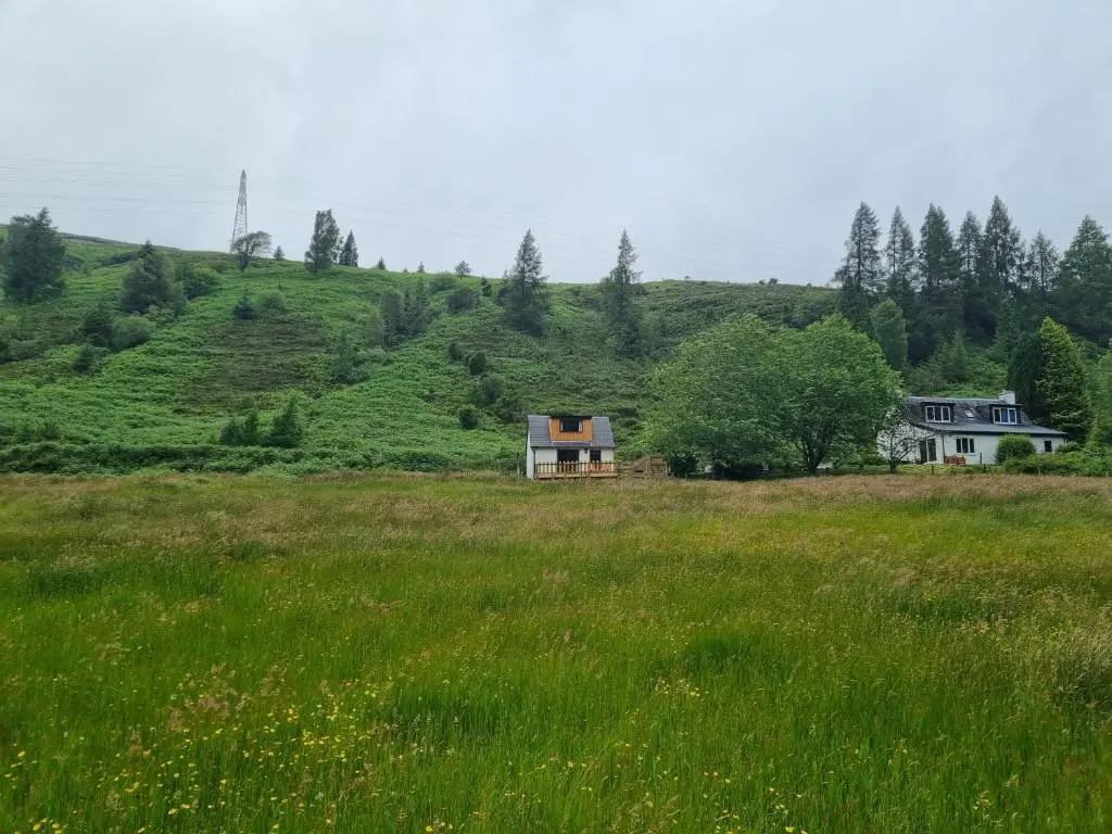a house in the middle of a field of grass at Cozy Nook in Spean Bridge