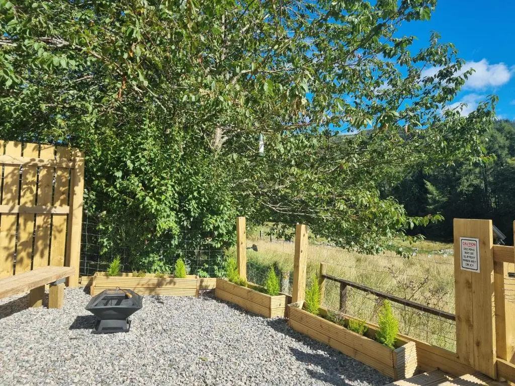 a garden with a charcoal grill and a fence at Cozy Nook in Spean Bridge