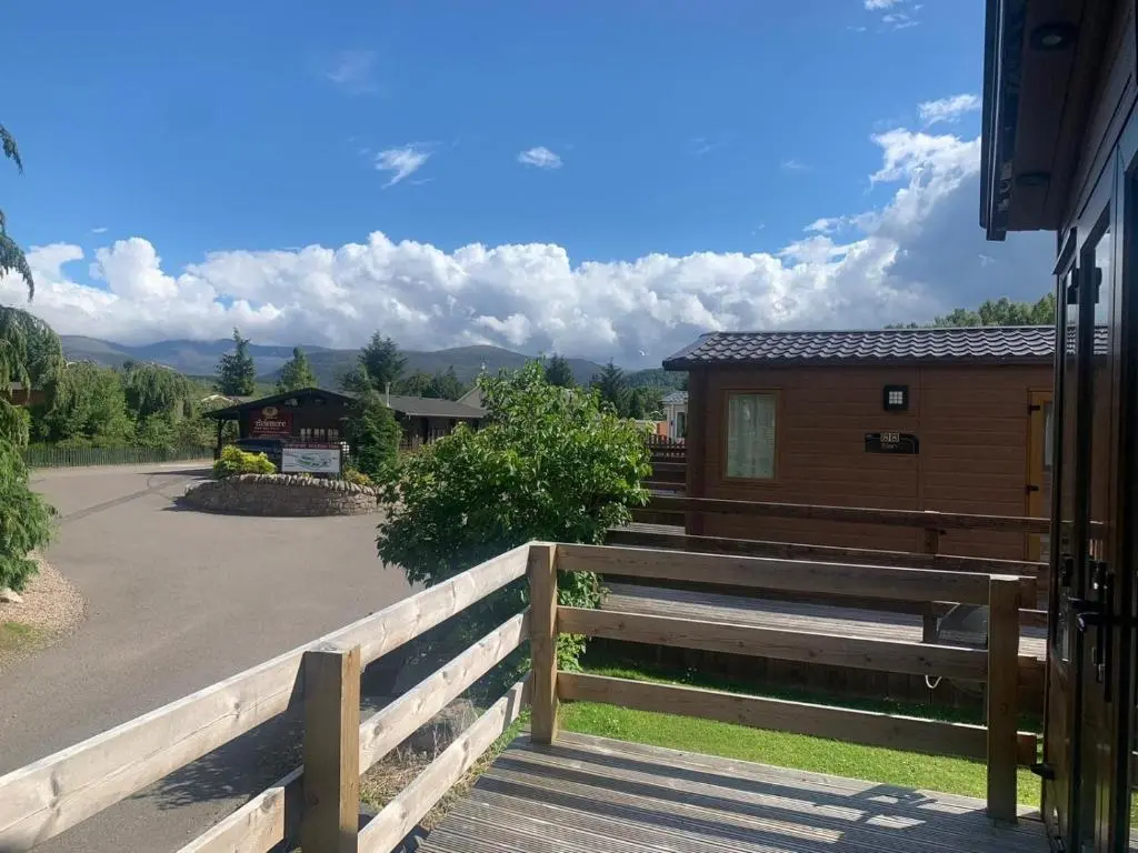 a wooden fence next to a house with a driveway at Feorag Lodge in Aviemore