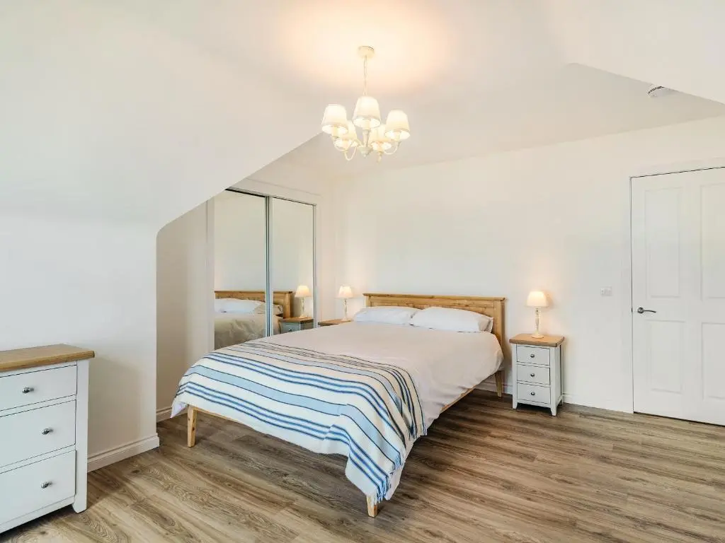 a white bedroom with a bed and a chandelier at Headland View in Banff