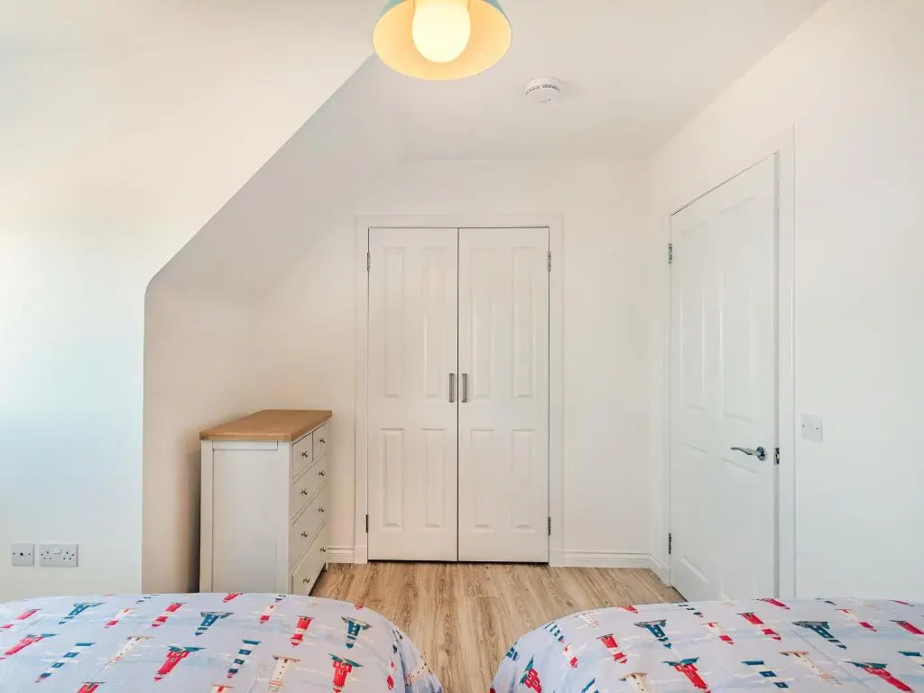 a white bedroom with a bed and a closet at Headland View in Banff
