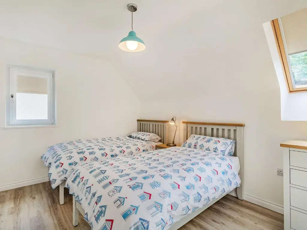 a bedroom with two beds and a desk and a window at Headland View in Banff