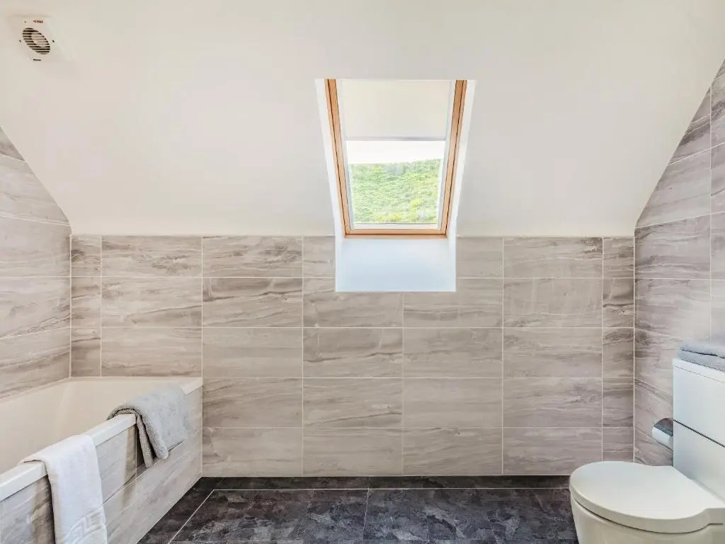 a bathroom with a tub and a window at Headland View in Banff