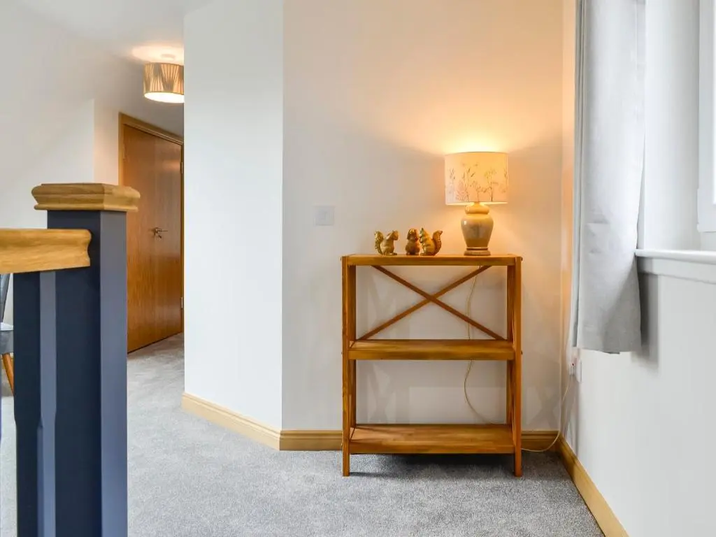 a hallway with a table with a lamp on it at Druids Knowe in Tarfside