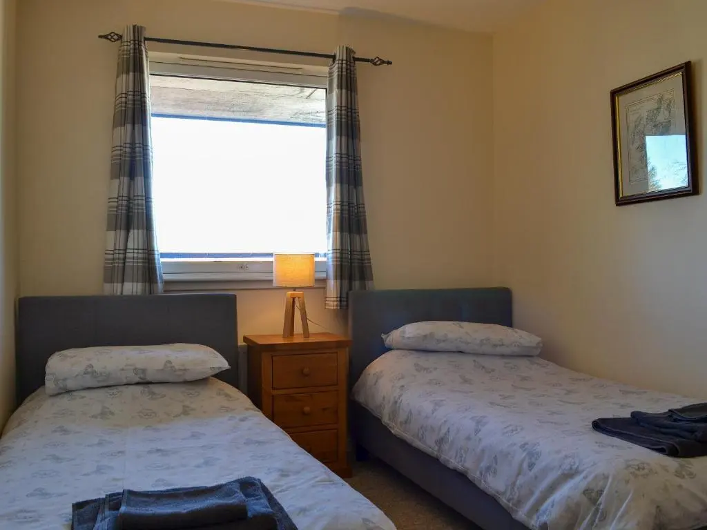 a bedroom with two beds and a window at Ness-Side Apartment in Inverness