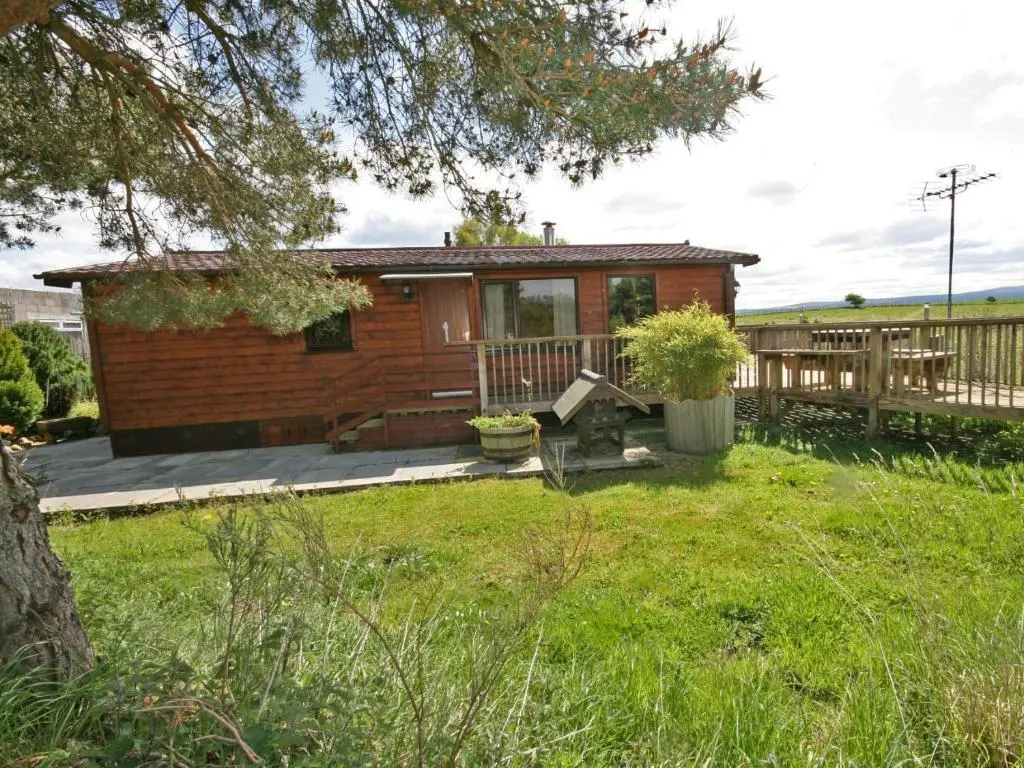 a small cabin with a porch and a deck at Henrys Lodge in Balblair