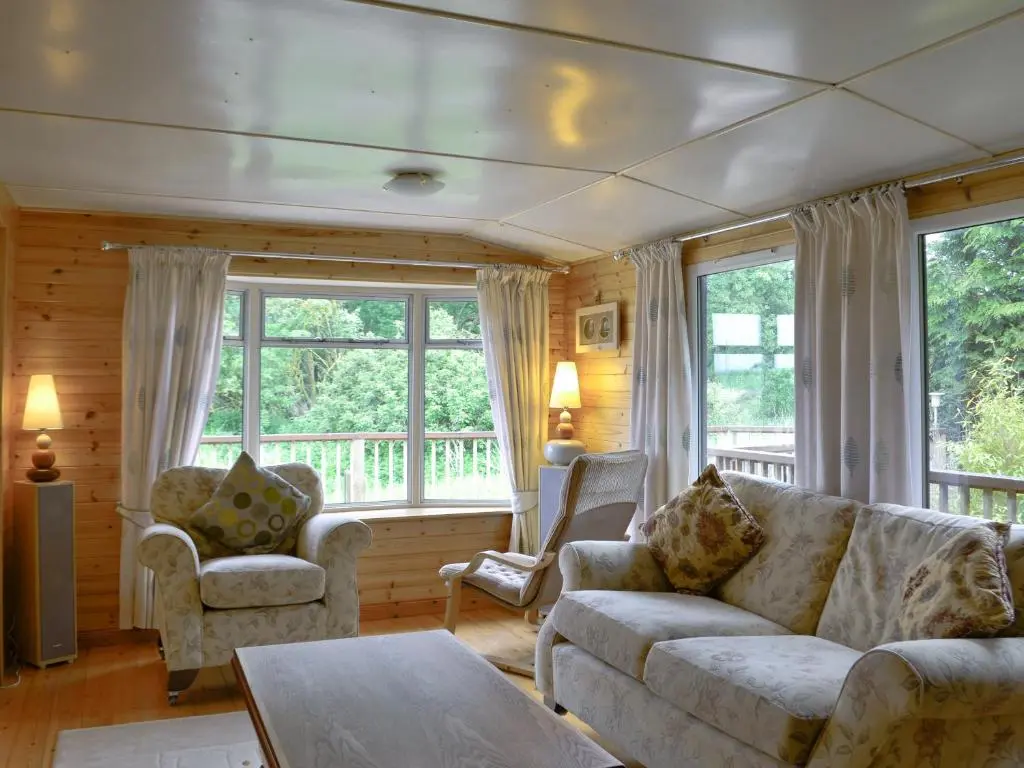 a living room with a couch and chairs and windows at Henrys Lodge in Balblair