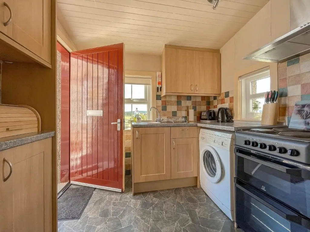 a kitchen with a stove and a washer and dryer at Rowan Cottage - Uk38991 in Dalcross