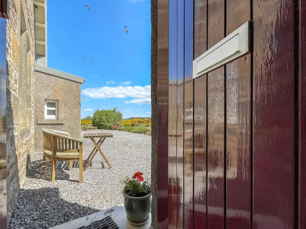 a door to a patio with a table and a bench at Rowan Cottage - Uk38991 in Dalcross