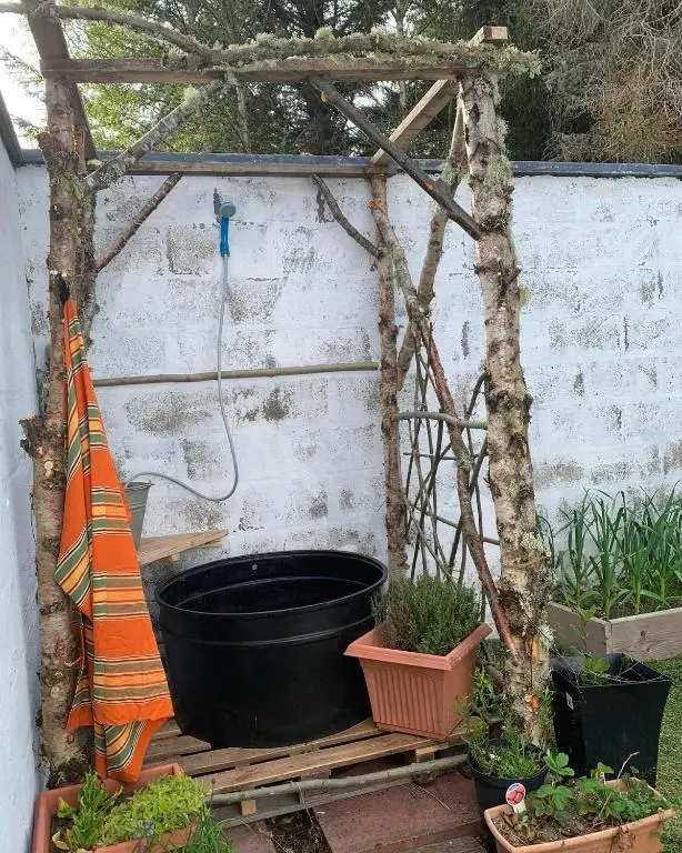 a pergola with a black bucket and some plants at Birkenshaw - Beautiful Shepherd\u2019s Hut in the Highlands. in Dornoch