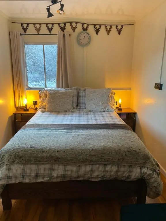 a bedroom with a bed with a clock on the wall at The Cabin, Stronua. A beautiful 1 bedroom cabin. in Fort Augustus