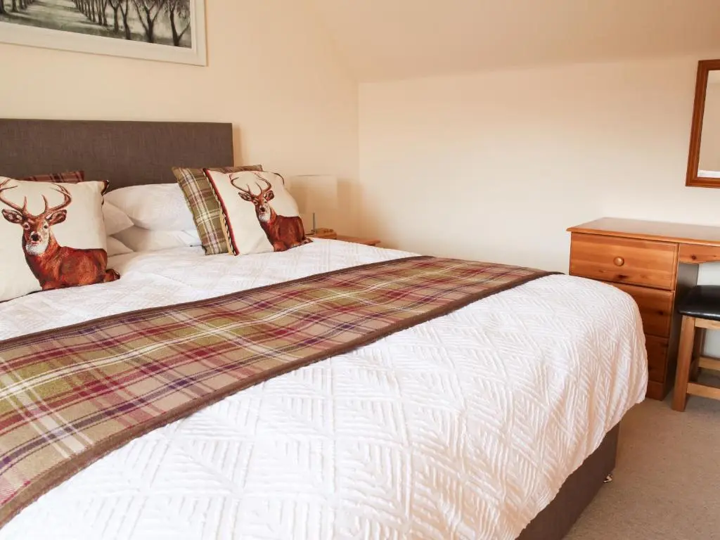 a bedroom with a bed with two deer pillows at Hill Cottage in Ardmair