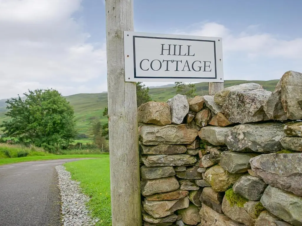 a sign for a hill cottage on a stone wall at Hill Cottage in Ardmair