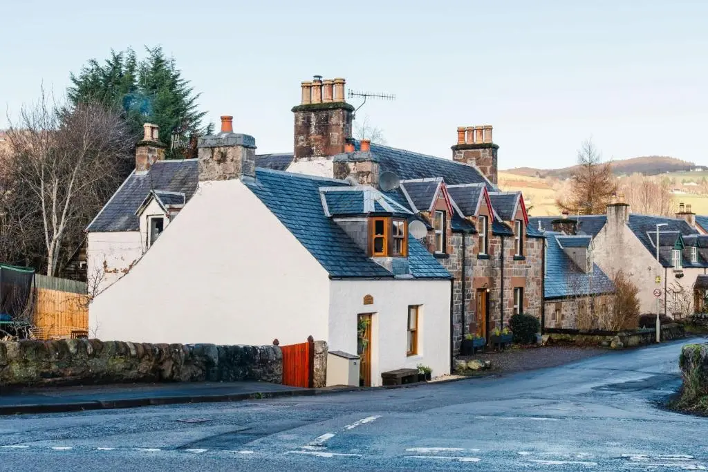 a large white house with chimneys on a street at Crossroads Cottage in Drumnadrochit