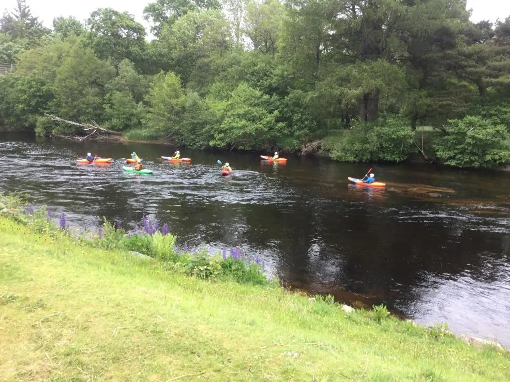 a group of people kayaking down a river at RIVERSIDE LODGE RETREAT in Aviemore