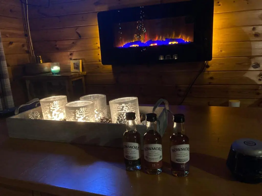 three bottles of beer sitting on a table with glasses at RIVERSIDE LODGE RETREAT in Aviemore