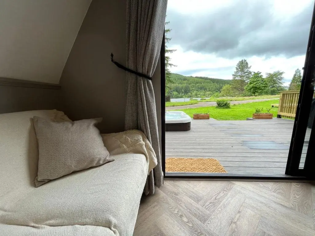 a room with a bed and a view of a deck at Bonnie Lodge-Lochside Location with Hot Tub in Invergarry