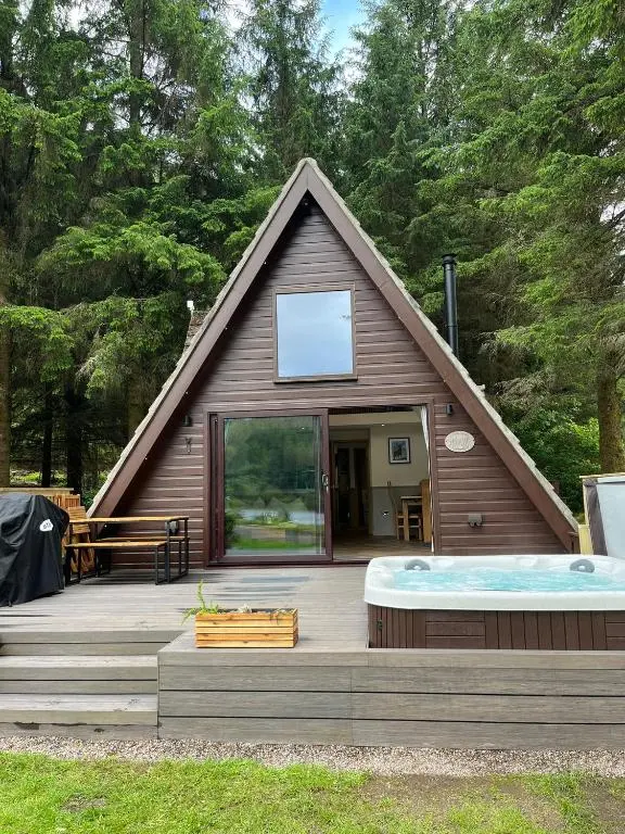 a large house with a hot tub in the yard at Bonnie Lodge-Lochside Location with Hot Tub in Invergarry