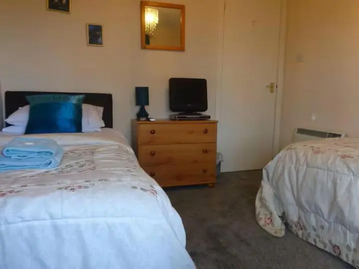 a bedroom with two beds and a television on a dresser at Aviemore Glenlivet Lodge in Aviemore