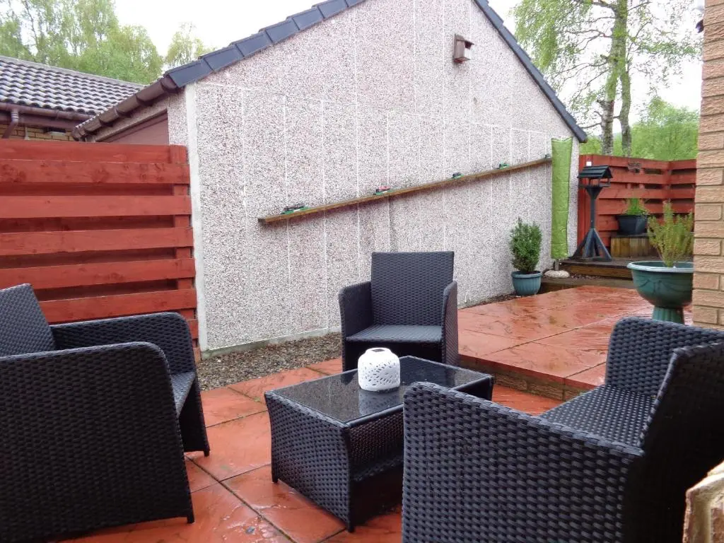a patio with chairs and a table and a fence at Aviemore Glenlivet Lodge in Aviemore