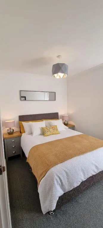 a bedroom with a large bed with white sheets at Rammal Lodge - Entire home, self catering apartment in Inverness in Inverness