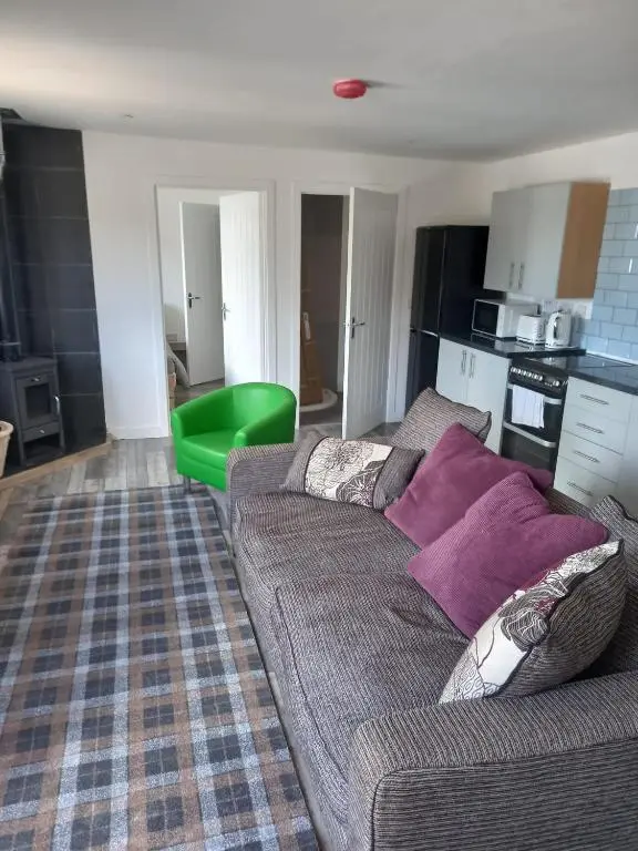 a living room with a couch and a kitchen at Full Pint in Tain