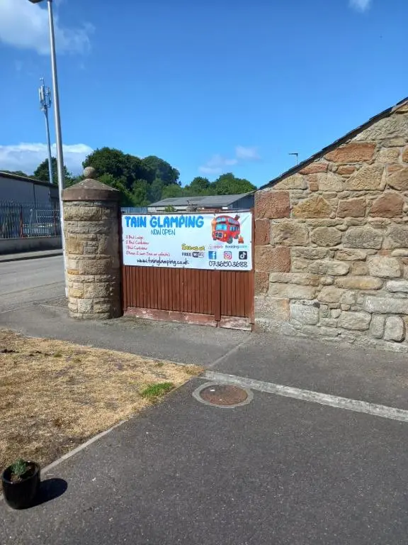 a sign on a brick wall with a fence at Wee Shot in Tain