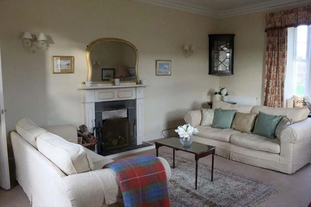 a living room with two couches and a fireplace at Garbity Farmhouse - beautiful 6-bedroom Farmhouse with open fires in Fochabers