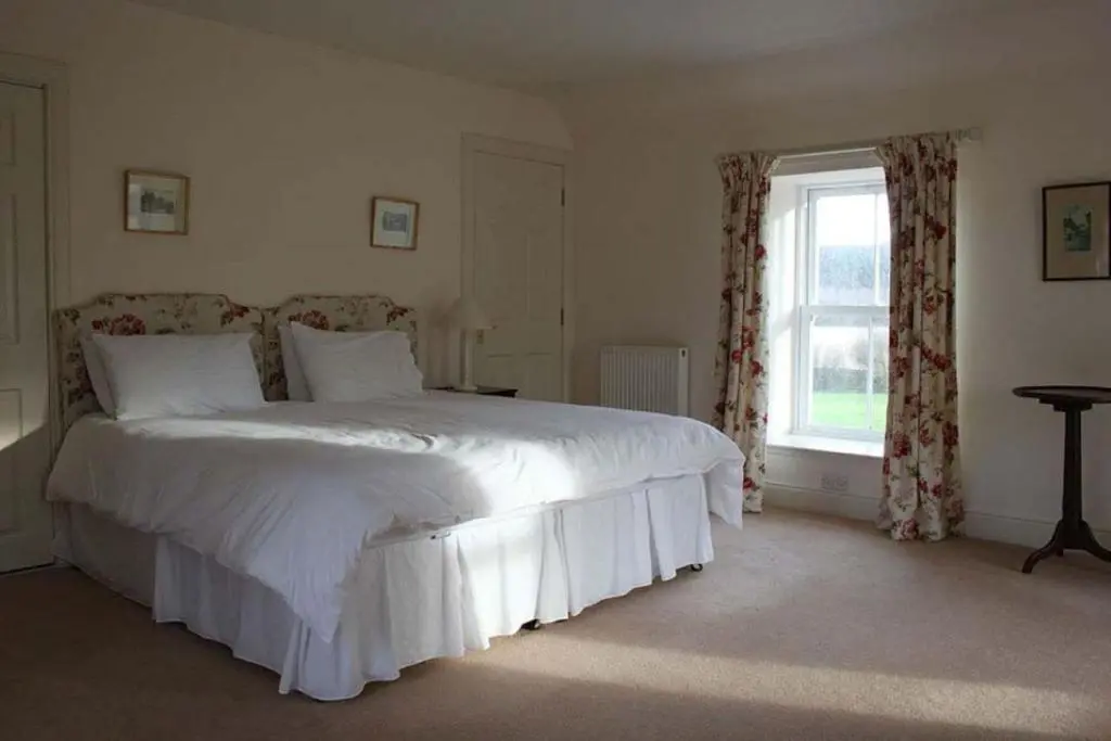 a bedroom with a large white bed and a window at Garbity Farmhouse - beautiful 6-bedroom Farmhouse with open fires in Fochabers