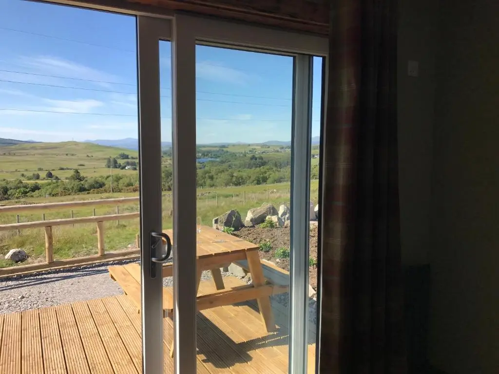 an open door to a deck with a picnic table at Ben Klibreck, Ben Hope, Ben Hee in Torroboll