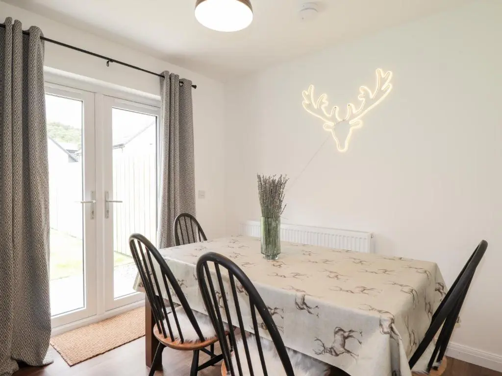 a dining room with a table and chairs and a window at 6 Bynack More in Aviemore
