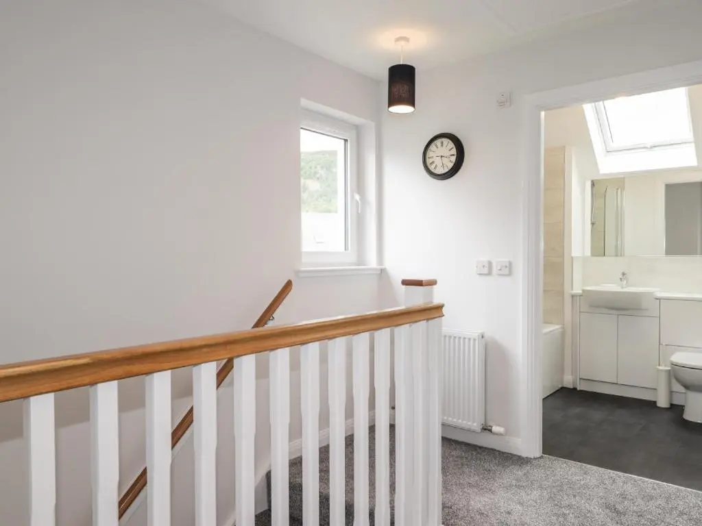 a bathroom with a staircase and a sink and a clock at 6 Bynack More in Aviemore