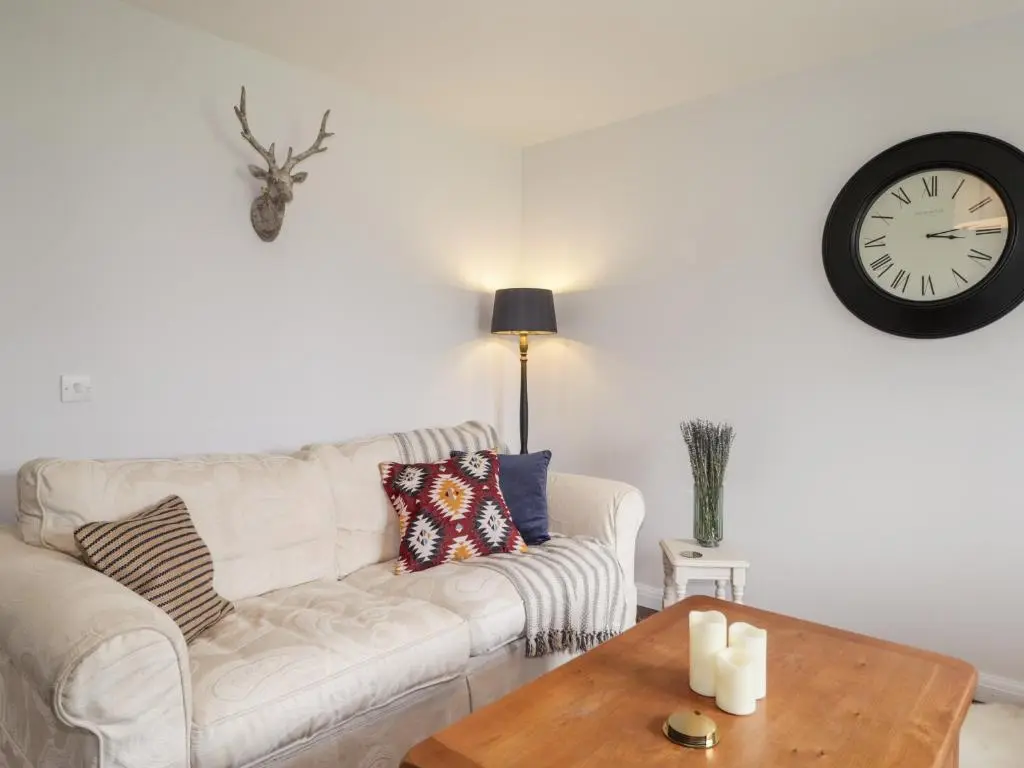 a living room with a couch and a clock on the wall at 6 Bynack More in Aviemore