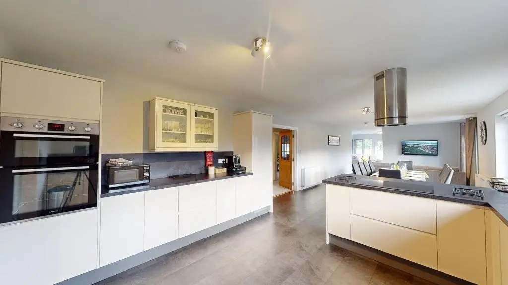 a kitchen with white cabinets and black counter tops at Braeside - Family home in Nethy Bridge in Nethy Bridge