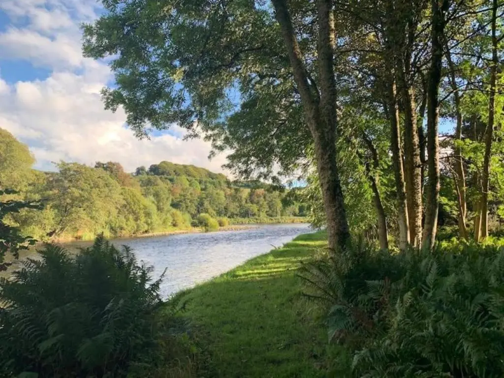 a view of a river with trees and a grass field at Bruntlands Steading in Fochabers