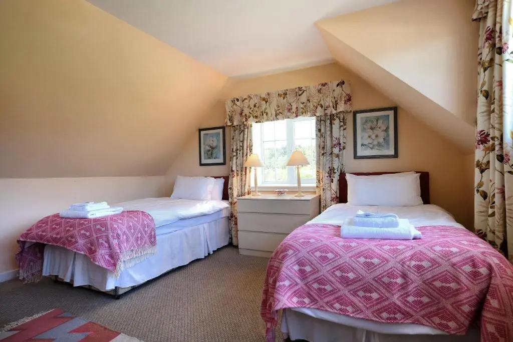 two twin beds in a room with a window at Bruntlands Steading in Fochabers