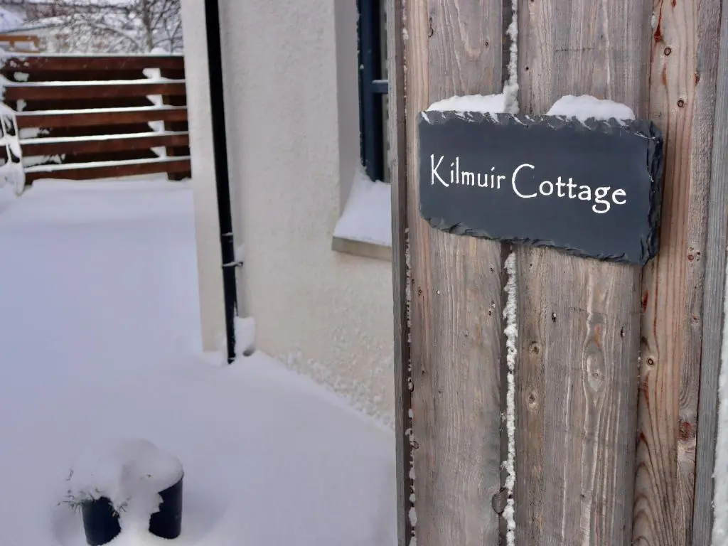 a sign on the side of a building in the snow at Kilmuir Cottage in Tomintoul
