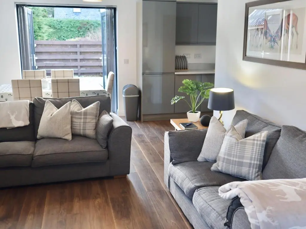 a living room with a couch and a table at Kilmuir Cottage in Tomintoul