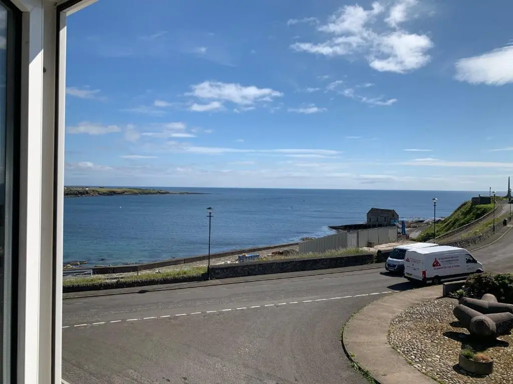 a road with a view of the ocean from a window at Caithness Stone house in Wick