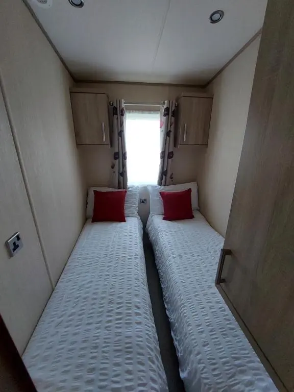 a small room with two beds in it with a window at Aurora Way 81 in Lossiemouth