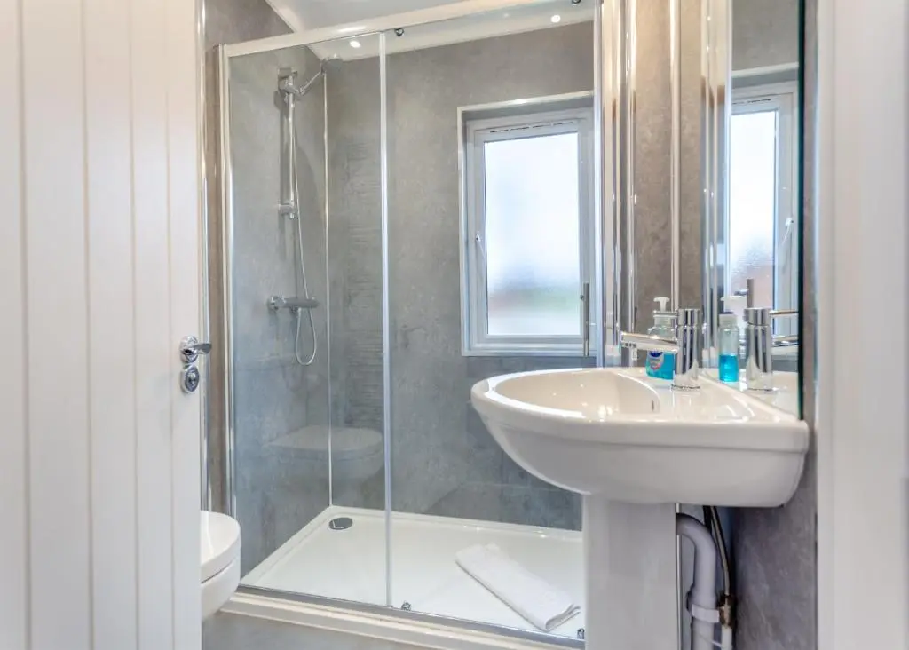 a bathroom with a sink and a glass shower at Castlewood Lodges in Strachan