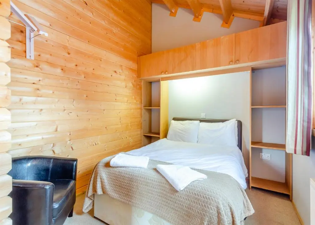 a bedroom with a bed in a wooden wall at Castlewood Lodges in Strachan