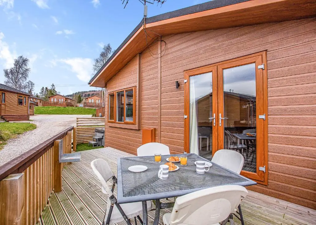 a patio with a table and chairs on a deck at Castlewood Lodges in Strachan