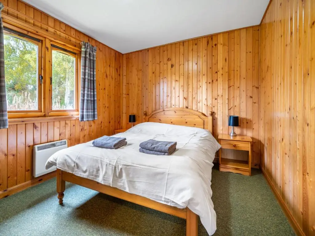 a bedroom with a bed in a wooden wall at Divach Lodge at Lochletter Lodges in Drumnadrochit